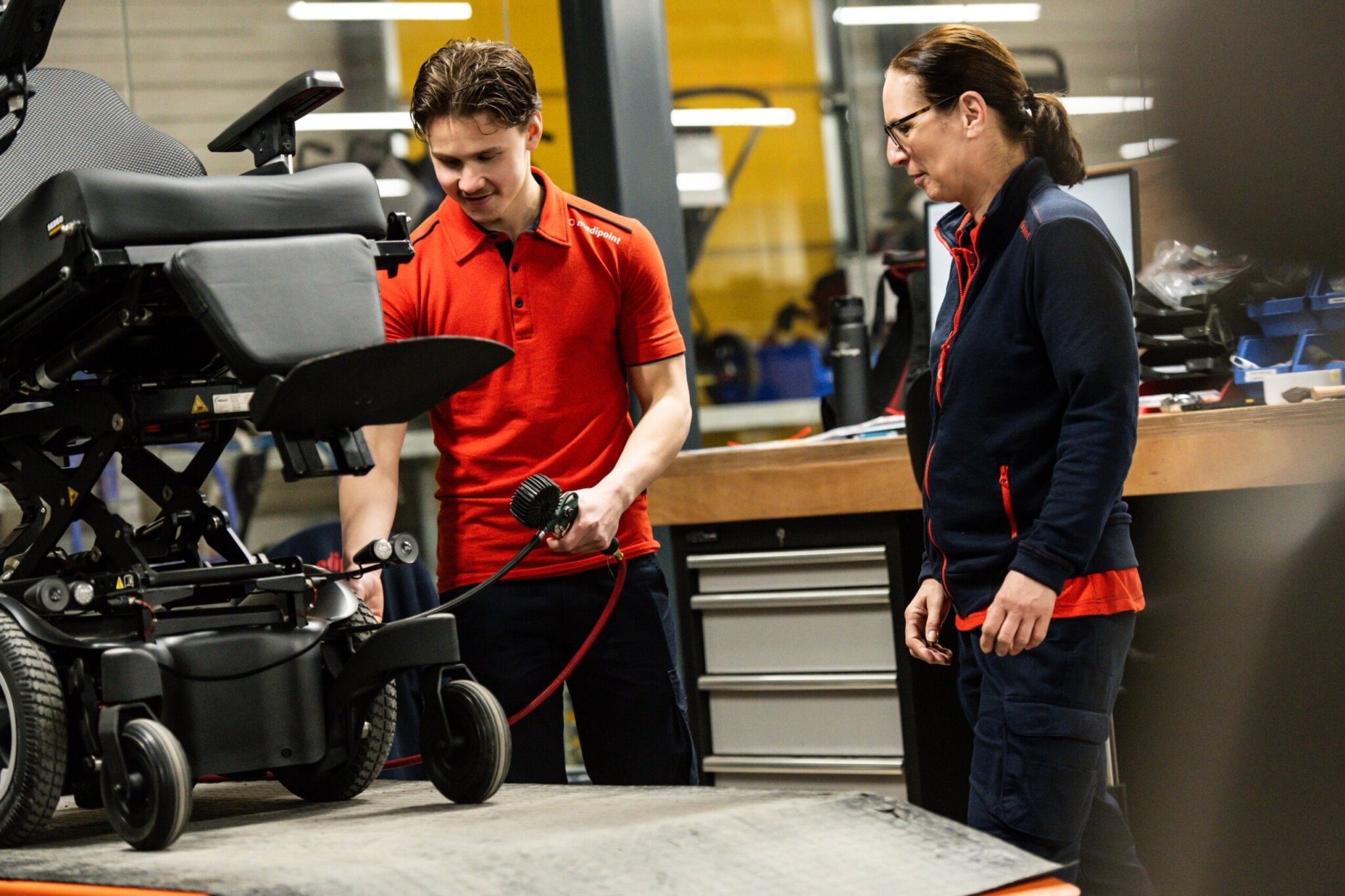 Foto van man die de banden oppompt van een rolstoel terwijl een vrouw toekijkt